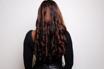 Person with long, wavy hair from behind on a plain background